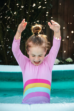 Excited child playing in backyard paddling pool, summer holiday