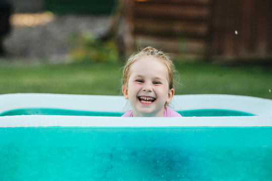 Playful child relaxing in inflatable backyard pool