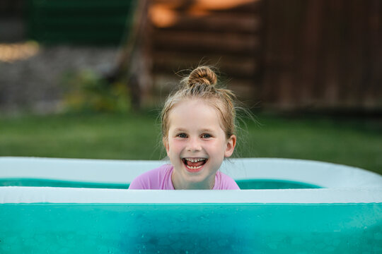 Playful child relaxing in inflatable backyard pool