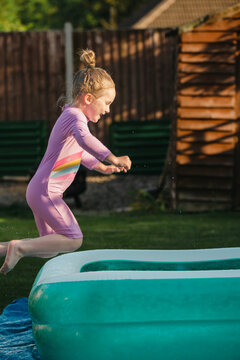 Child jumping into inflatable backyard pool in summer