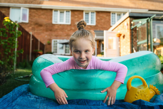 Playful child relaxing in inflatable backyard pool