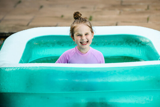 Playful child relaxing in inflatable backyard pool, summer holiday