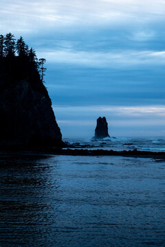 Silhouetted cliff and sea stack at blue hour