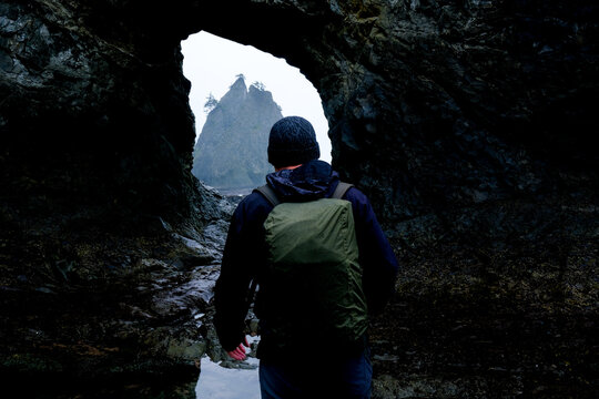 Hiker with backpack walks through a coastal cave