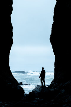 Silhouette of a man watching waves from a sea cave