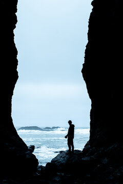 Person silhouetted in a cave looking at the ocean