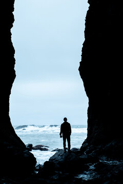 Silhouetted man framed by a sea cave entrance