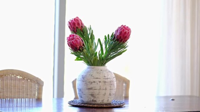 Proteas in a ceramic vase on a dining table in a home