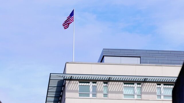 Large American flag flying ontop of a modern embassy building in Berlin