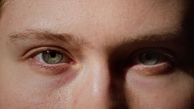 Close up shot of unrecognizable young woman opening eyes and looking at camera with sunlight accentuating striking green eyes and real face texture, copy space