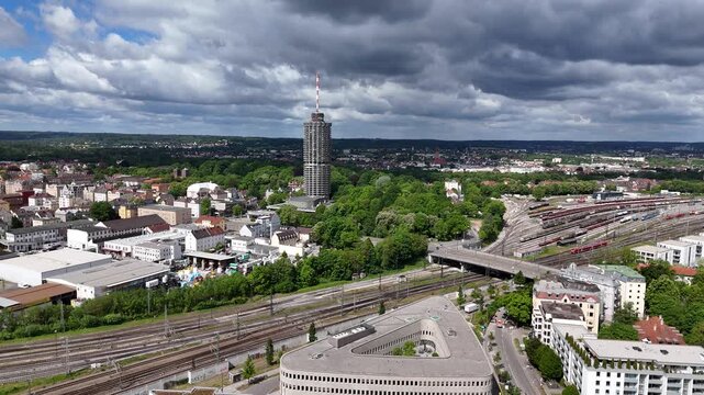 Aerial movement from church direction toward Hotelturm with railway, park and city details.