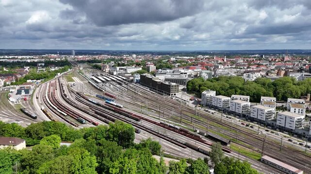 Drone flight moving left to right over Augsburg railway station and surrounding modern buildings.