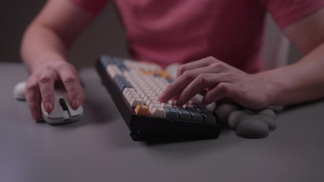 Gamer hands typing on modern mechanical keyboard and using a computer mouse with special ergonomic pad, preventing carpal tunnel syndrome while working or gaming, close-up, slow motion.