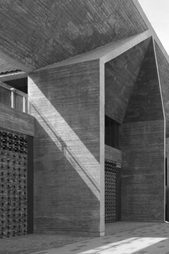 Monochrome photograph of brutalist concrete architecture emphasizing bold geometric forms, textured surfaces and dramatic diagonal shadows; a minimalist urban composition conveying solidity, austerity