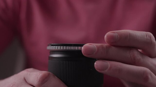 Close up of photographer hands unscrewing and removing circular polarizing filter from modern camera lens as part of regular maintenance and cleaning routine.