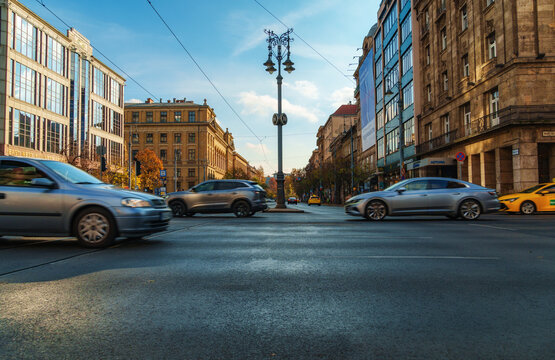 Motion blur of cars driving on a busy city street in Budapest Hungary with historic architecture and beautiful street lamps under a clear blue sky during daytime