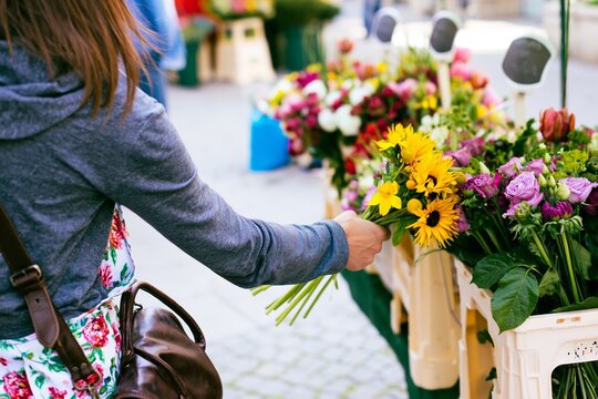 Woman picking sunflower bouquet at outdoor floral market