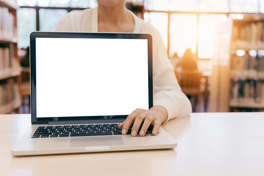 Student using laptop with blank screen in modern library