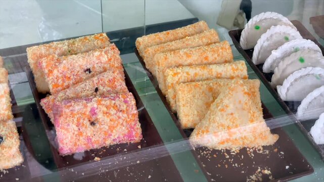Various traditional indonesian snacks risoles and cireng displayed in a glass showcase.
