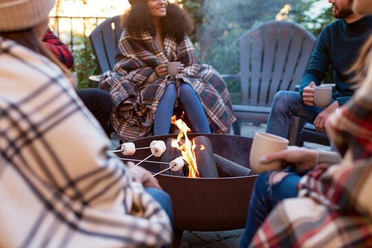 Friends gathered around outdoor fire pit with blankets and drinks