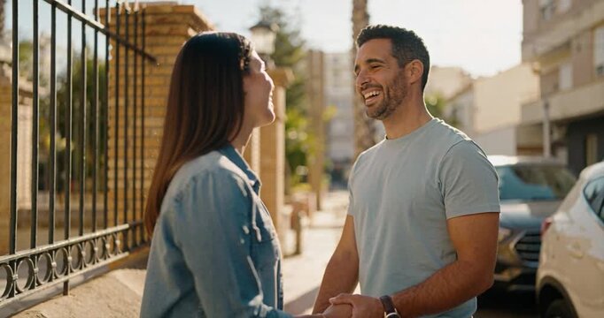 Couple conversing outdoors near fence and vehicles