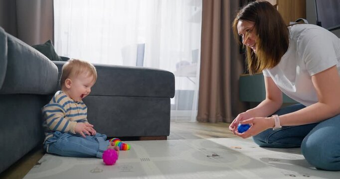 A joyful interaction between a mother and her baby playing with colorful toys on a living room floor, capturing moments of bonding, play, and early childhood development in a cozy home environment