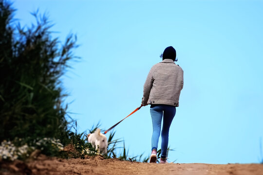 A woman walking with her dog on a leash