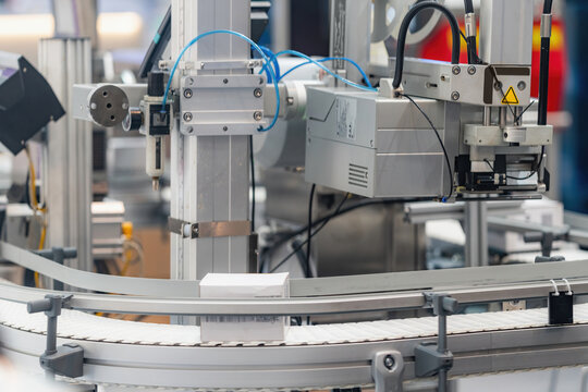 Automated conveyor belt system with mechanical components and pneumatic elements operates at an indoor industrial facility, demonstrating modern production line and assembly automation technology.
