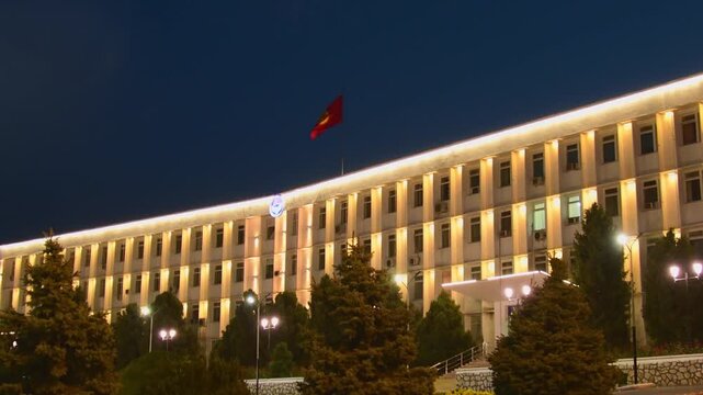 Osh, Kyrgyzstan - september 15th, 2025: Osh City Hall at night, Kyrgyzstan. Soviet Modernist architecture with illuminated facade and national flag central square. Historic administrative building.
