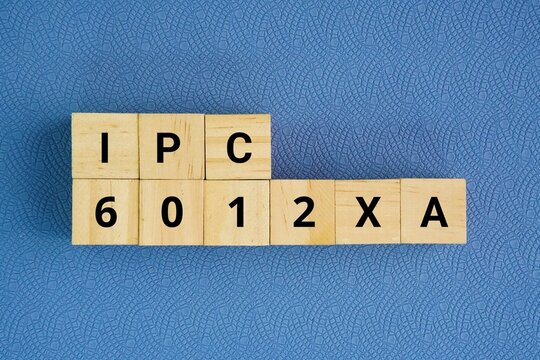 Wooden cube with words IPC-6012XA. the industry-specific addendum for automotive applications to the base IPC-6012 standard, which governs the qualification and performance specifications 
