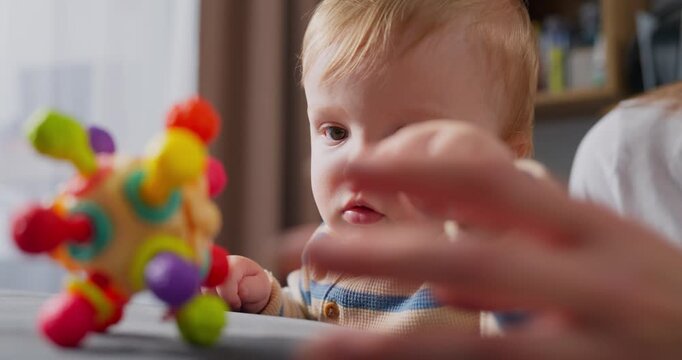 Curious toddler exploring and playing with a colorful sensory toy at home, developing fine motor skills and cognitive abilities through hands-on interaction and discovery