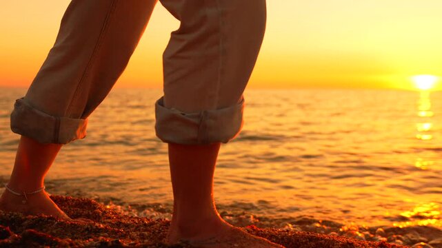 Walking sunset beach barefoot person strolls along pebble shoreline during a golden sunset reflecting serenity and peace
