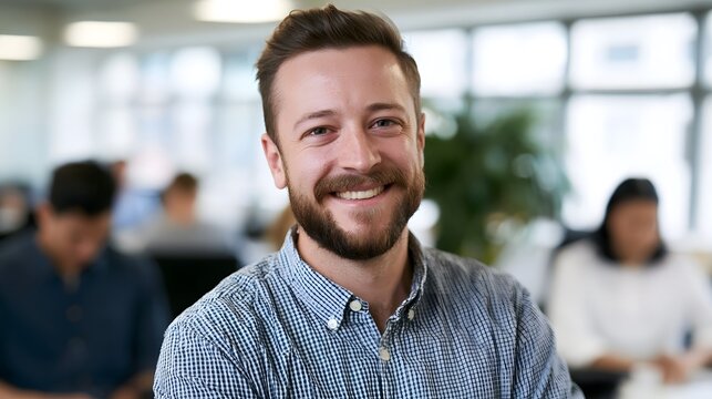 A smiling man in a professional setting enjoys collabo n within a modern office illuminated by natural daylight