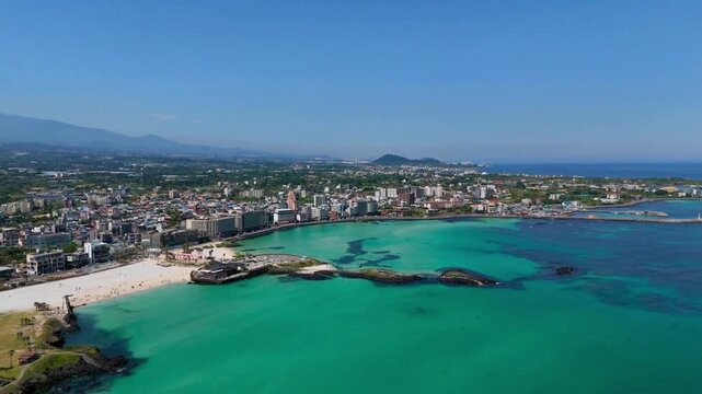 Aerial panorama of Hamdeok beach town and a turquoise bay with Hallasan mountain on the horizon, Jeju Island, South Korea