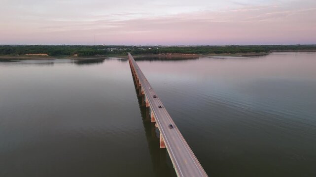 Aerial drone footage over Mile Long Bridge at Saylorville Lake Iowa with the wooden deck and railing extending across calm still water under overcast twilight sky