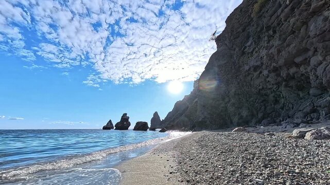 Beach ocean coastline panoramic view of a rocky shore meeting clear blue waters under a sunny summer sky for travel background