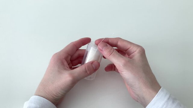 A woman takes out dental floss from a box on a white background. Daily oral care and fresh breathing routine. A confident, beautiful smile and a feeling of cleanliness throughout the day