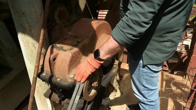 A hand touches the working motor of a large crusher.
