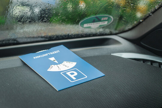 European parking disc on vehicle dashboard with rainy windshield background