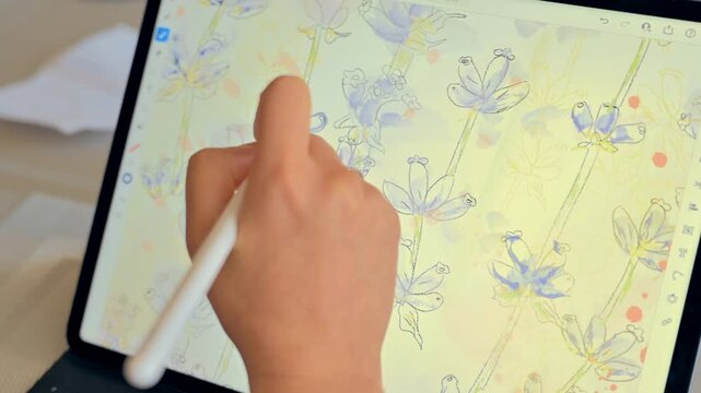 Digital artist working on beautiful watercolor floral pattern illustration using tablet and stylus pen.