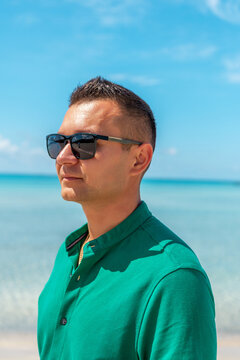 Happy guy in a green shirt on sea background.
