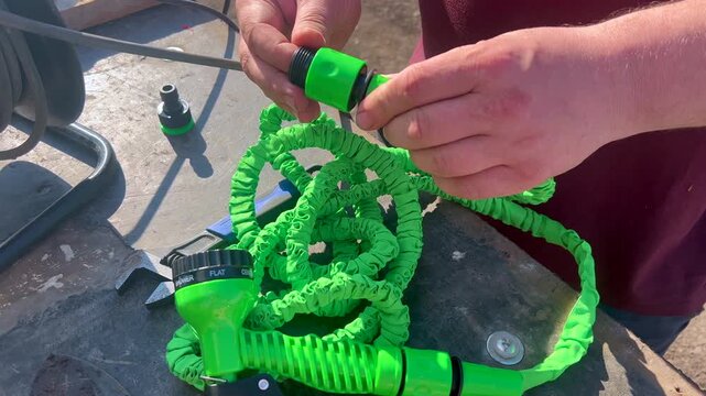 Person assembling green expandable garden hose