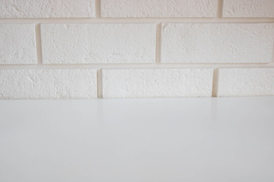 A glossy, empty table surface against a white brick wall