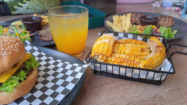 Gourmet steak house platter featuring Rib Eye, Sirloin, and Ribs Corn with a large double-meat burger. Cinematic camera movements from close-up to eagle eye view. Luxury dining experience. 4K.