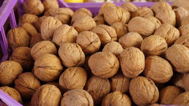 A generous pile of fresh walnuts at an Italian produce market, a beloved autumn treasure deeply rooted in Italian culinary tradition, perfect for desserts, sauces and rustic dishes.