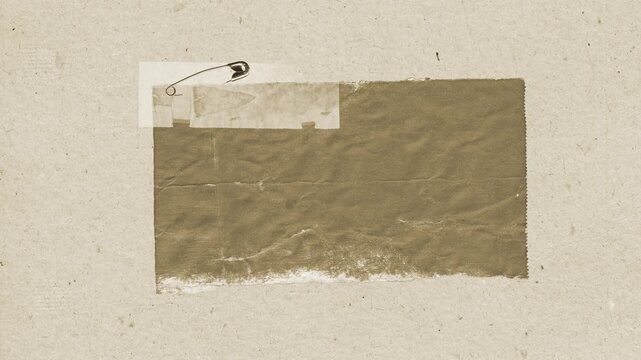 Textured brown paper rectangle pinned with a metal safety pin against a neutral backdrop in this high resolution motion video