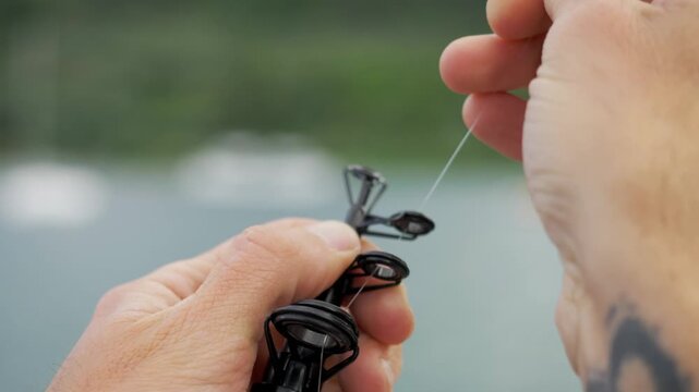 Man's Hands Threading Fishing Line Through Rod Guides Before Fishing