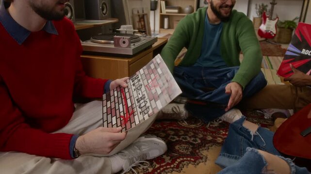 Group of friends looking at different vynyl records while girl holding guitar, sitting together on cozy living room floor