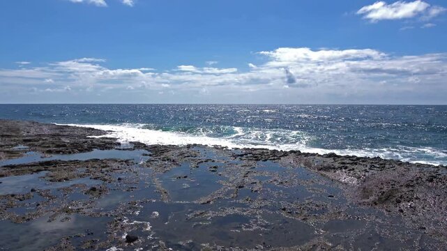 Sea waves crashing rugged volcanic rocky shore