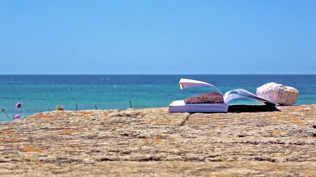 Open book with rock on beach by ocean